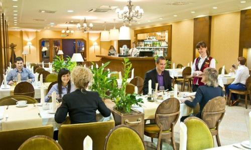 a group of people sitting at tables in a restaurant at GRAND HOTEL Kielce in Kielce