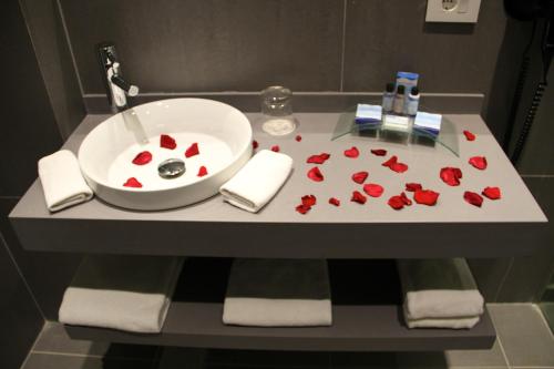 a bathroom sink with red rose petals on it at Pangea Beach Resort in Jiyeh