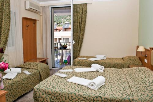 a hotel room with two beds and a window at Tolon Holidays Hotel in Tolo