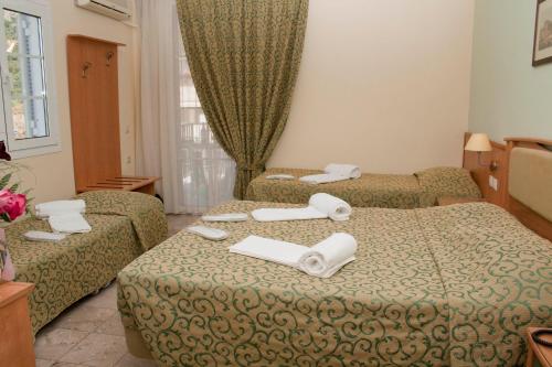 a hotel room with two beds with towels on them at Tolon Holidays Hotel in Tolo