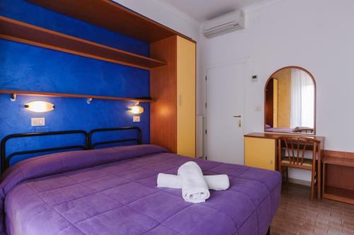 a bedroom with a purple bed with towels on it at Hotel Viking in Rimini