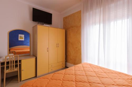a bedroom with a bed and a dresser with a television at Hotel Viking in Rimini