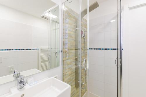 a white bathroom with a shower and a sink at Hotel Viking in Rimini