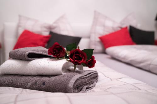 a pile of towels and roses on a bed at Pension & Restaurant La Amalia in Bad Sauerbrunn