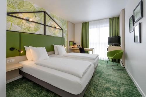 a hotel room with two beds and a green wall at Mercure Hotel Hannover Mitte in Hannover