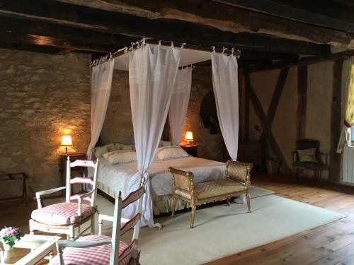 een slaapkamer met een hemelbed en 2 stoelen bij Villa La Roseraie avec accès piscine Hôtel La Roseraie in Montignac