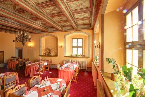 a restaurant with tables and chairs and a chandelier at Gotikhotel Frenzelhof in Görlitz