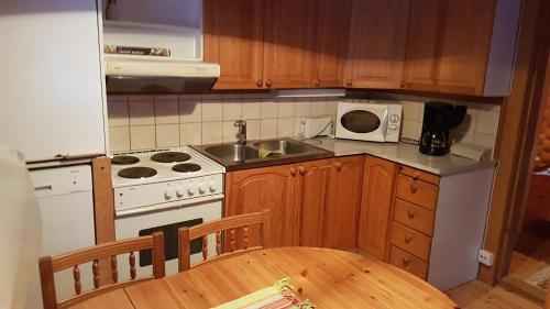 uma cozinha com um fogão, um lavatório e uma mesa em Kalajärven Lomakylä em Peräseinäjoki