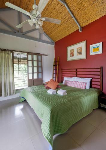 a bedroom with a green bed with a ceiling fan at The Duyan House at Sinagtala Resort in Orani