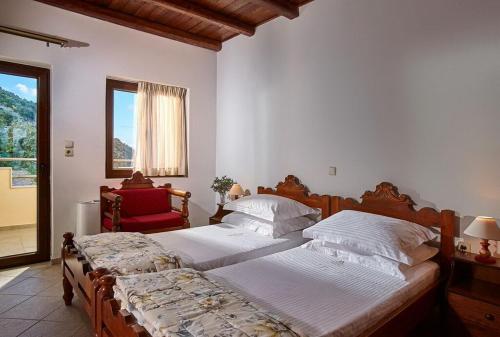 a bedroom with two beds and a red chair at Archontiko Manias in Axós