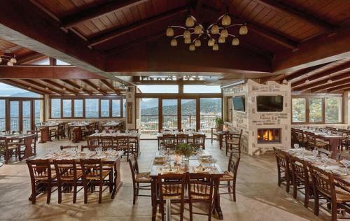 a dining room with tables and chairs and a fireplace at Archontiko Manias in Axós