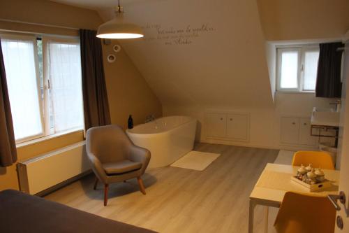 a bathroom with a bath tub and a chair at Saffels Nest in Lochristi