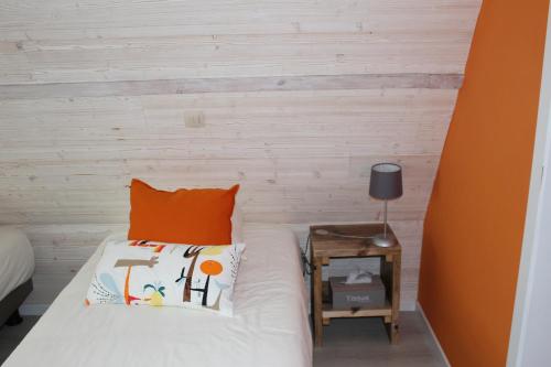 a bed with an orange pillow and a side table at Saffels Nest in Lochristi