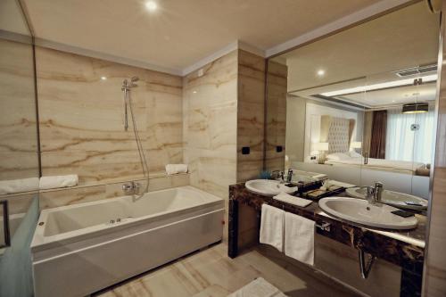a bathroom with two sinks and a bath tub and a tubermott at Premium Beach Hotel in Golem