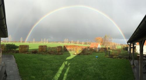 a rainbow in the sky over a yard at B&B De Hostelier in Ursel