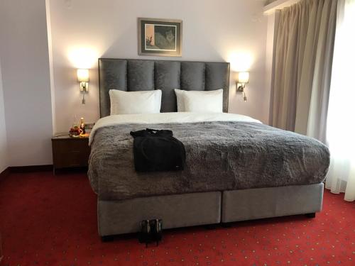 a bedroom with a large bed with a black bag on it at Art 'Otel in Sofia