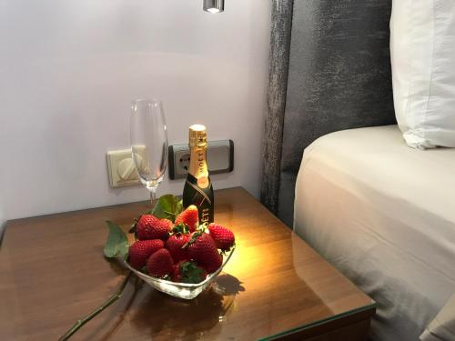 a bowl of strawberries and a bottle of wine on a table at Art 'Otel in Sofia