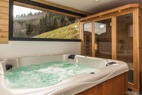 a bath tub in a room with a large window at La Ferme du Nol in La Bresse