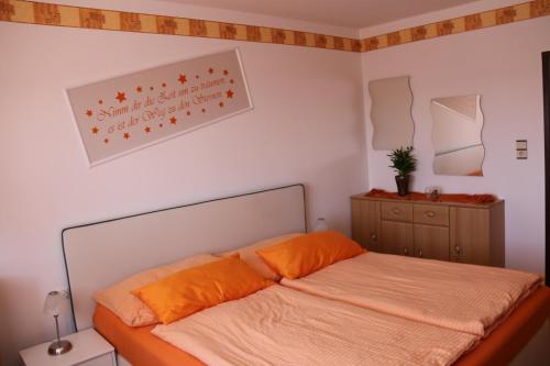a bedroom with a bed with orange pillows on it at Ferienwohnung Höbart in Dorfstetten