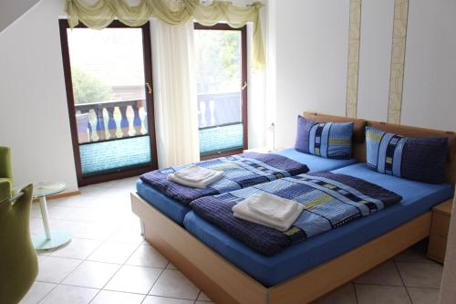 a bedroom with a blue bed with two windows at Landhaus Burs in Löningen