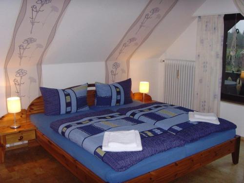 a bedroom with a large bed with blue comforter and pillows at Landhaus Burs in Löningen