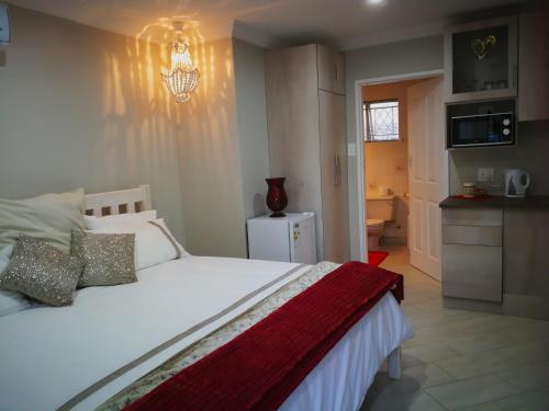 a bedroom with a white bed and a kitchen at Chic Breeze in Bloemfontein