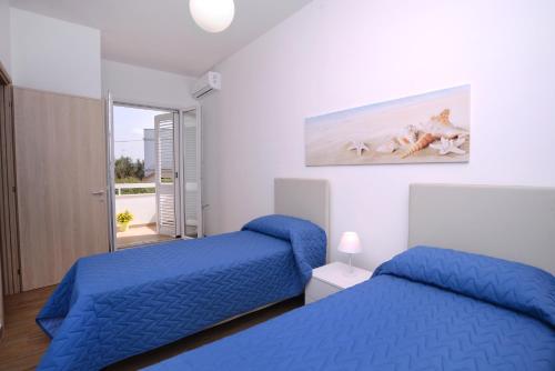 a bedroom with two beds and a painting on the wall at Altomare Case Vacanza in Porto Cesareo