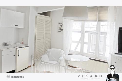 une cuisine avec des placards blancs, une table et une fenêtre dans l'établissement Vikaro, à Monschau
