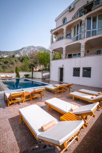 a group of lounge chairs and a pool in front of a building at Villa Del Mar in Sutomore
