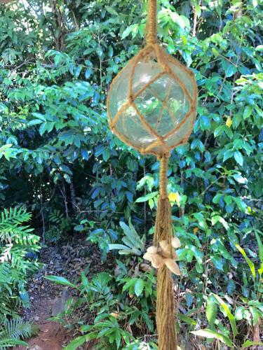 a glass orb hanging from a rope in front of a bush at Daintree Magic Holiday House in Cow Bay