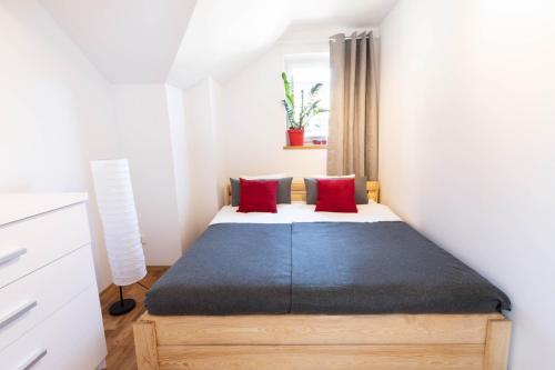 a bedroom with a bed with two red pillows at Halna Residence in Krynica Zdrój