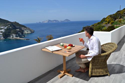 a man sitting at a table with a drink at Maridea Casa Vacanza- Le Alcove sul Mare Suites in Ponza