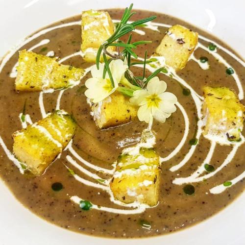 a plate of soup with bread and flowers on it at Agriturismo Treterre in Pianello Del Lario