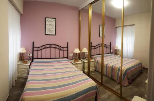 コルドバにあるDS Asturias - Puente Romanoのベッドルーム1室(ピンクの壁と鏡付きのベッド2台付)