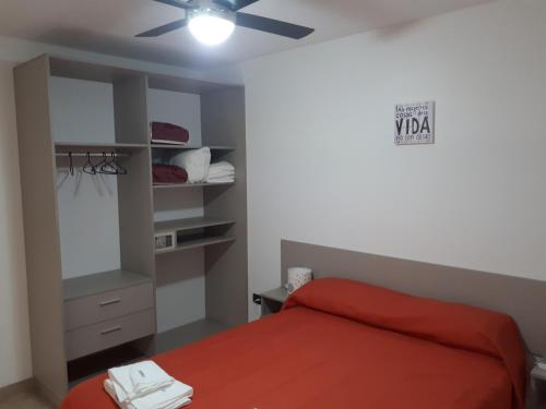 1 dormitorio con cama roja y ventilador de techo en Kawsay Complejo de Cabañas en San Antonio de Arredondo