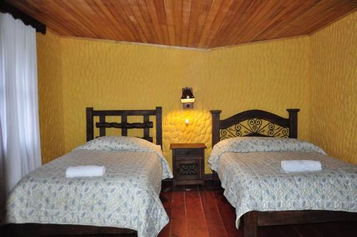a bedroom with two beds and a yellow wall at Hotel Museo la Posada del Molino in El Cocuy