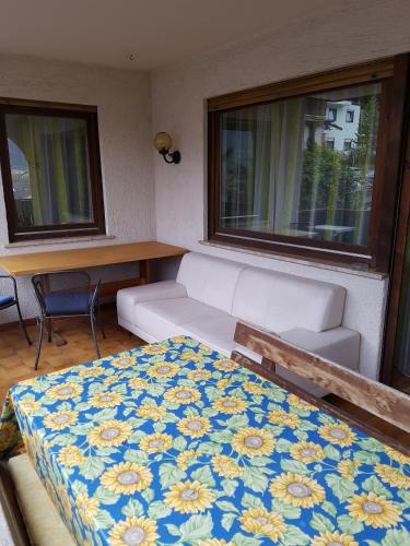 a room with a bed and a couch and two windows at Das Sonnenheim in Marlengo