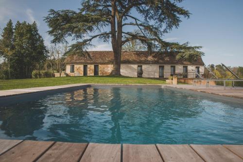 une piscine en face d'une maison avec un arbre dans l'établissement Villa Korum, à Bergerac