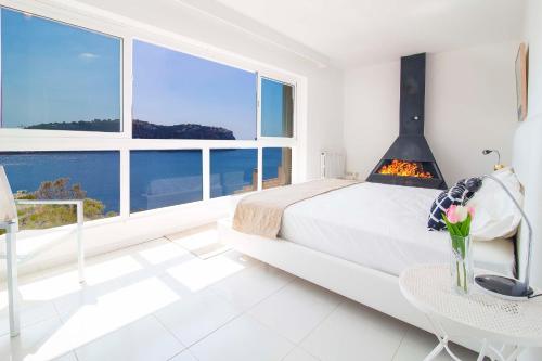 ポルト・ダンドラッチにあるFantastic Villa Port d'Andratxの白いベッドルーム(ベッド1台、暖炉付)