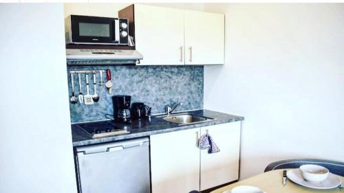 une petite cuisine avec un évier et un micro-ondes dans l'établissement Studio à 1 kilomètre de Disneyland Paris, à Montévrain