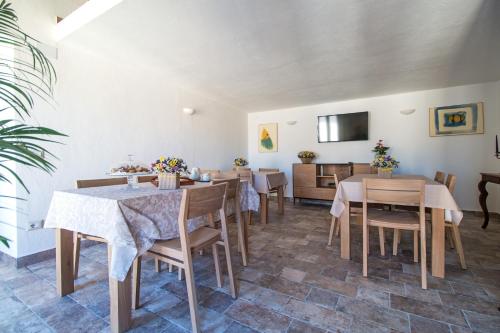 a dining room with tables and chairs and a tv at Karama in Dorgali