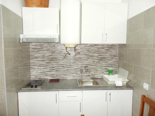 una cocina con armarios blancos y fregadero en Apartamentos Turísticos Pérola da Rocha II en Portimão