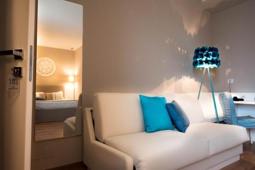 a living room with a white couch with blue pillows at Hotel Mediterraneo in Lido di Latina 