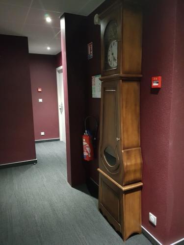 a large grandfather clock in a room with a fire extinguisher at Hôtel Jeanne D'Arc in Saint-Chély-dʼApcher