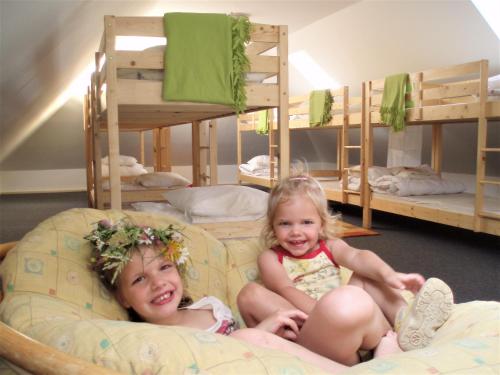 two little girls sitting on a chair in a room with bunk beds at Magdolna Ház in Szögliget