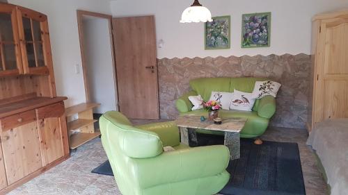 a living room with a green couch and a table at Pension Tannenspitze in Lutherstadt Wittenberg