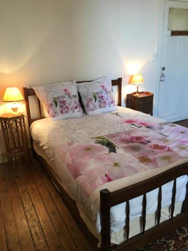 Un dormitorio con una cama con flores rosas. en Gite chez Cyrano en Bergerac
