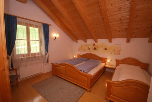 1 dormitorio con 2 camas, ventana y techos de madera en Im Kranzhof, en San Candido
