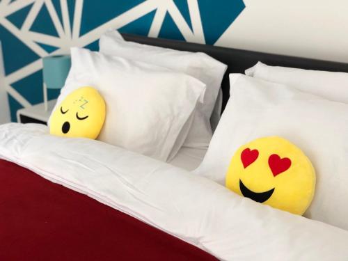 deux oreillers sur un lit avec sourire dans l'établissement La Suite Emoji - SDP, à Lagny-sur-Marne