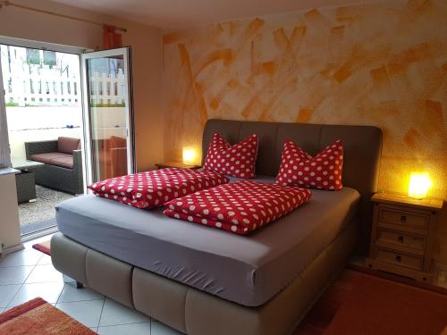 a bed with red pillows on it in a room at Gästehaus Rana in Rust